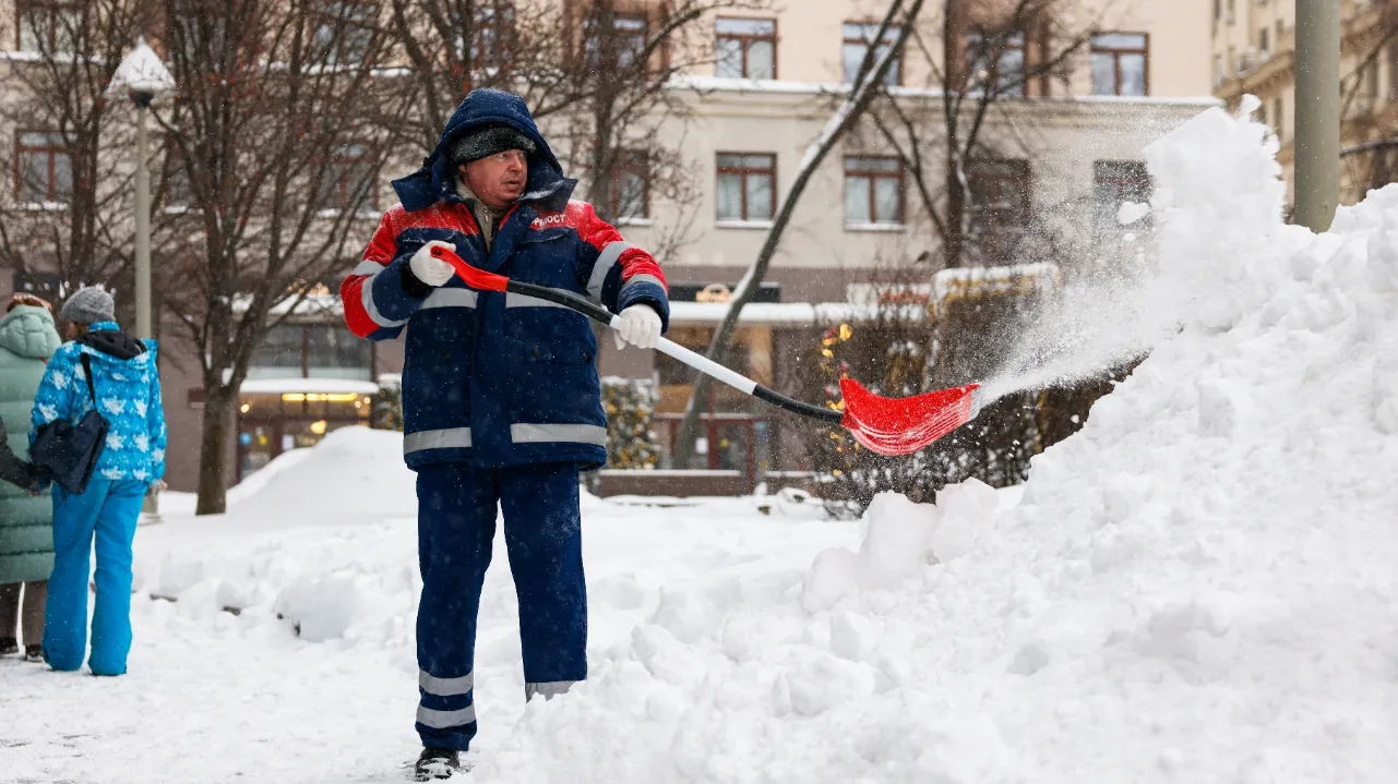Россия. Москва. Работник коммунальных служб в сквере Шмелева во время снегопада.