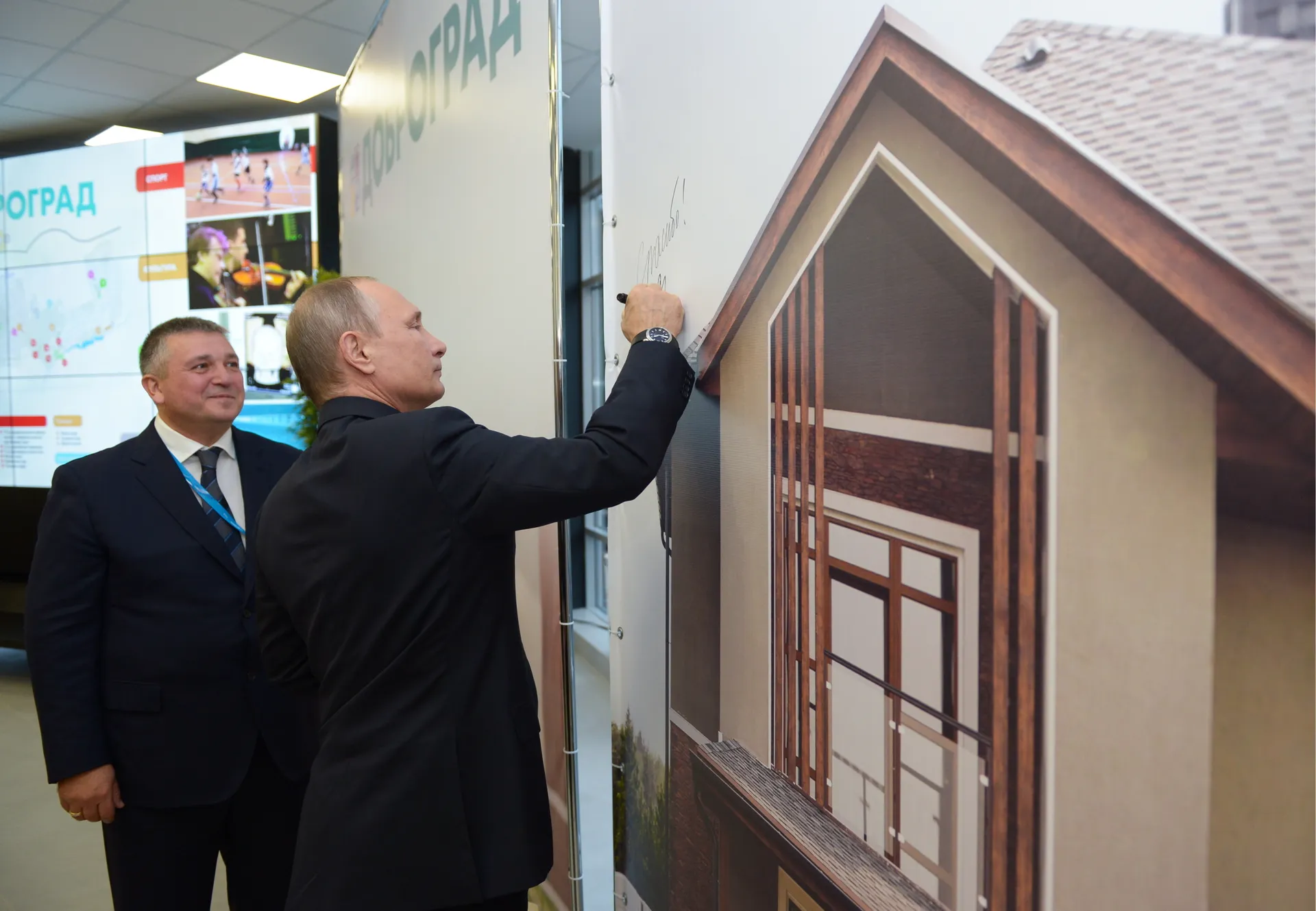 Президент России Владимир Путин (справа) оставляет автограф на мультимедийном стенде спортивного курорта «Доброград» в Коврове. Слева — бывший совладелец компании «Аскона» Владимир Седов.