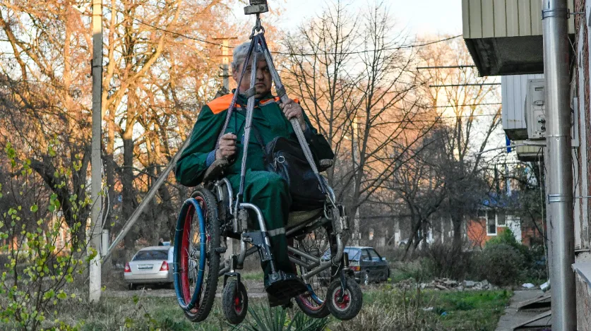 Краснодарский край. Тимашевск. Инвалид-колясочник Александр Юдин во время подъема в свою квартиру на самодельном лифте. В трехэтажном доме Александра узкие проходы, что не позволяет установить пандус.