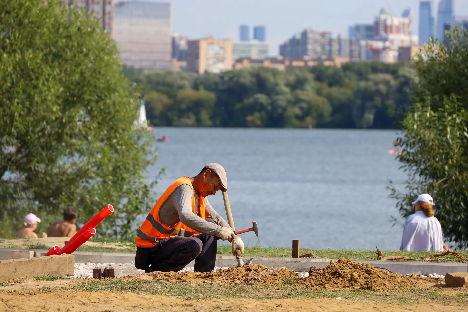 Россия. Москва. Работник коммунальных служб во время работ по благоустройству на городском пляже в Строгино.